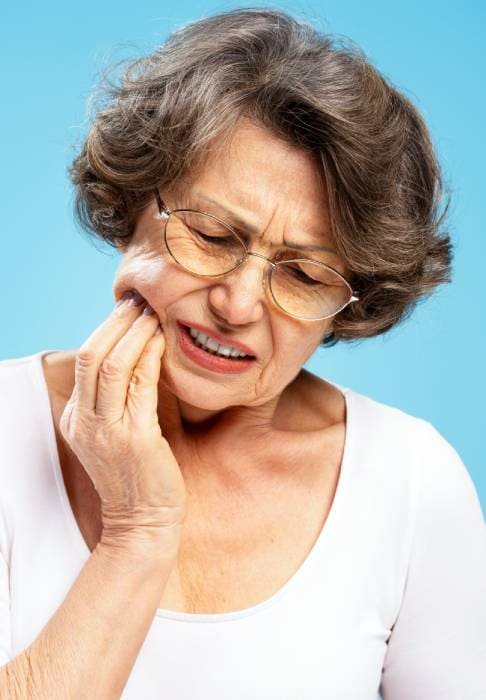 Dolore o fastidio ai denti - Paziente che si tiene una mano sulla guancia perché ha evidente male ai denti - Studio Berton
