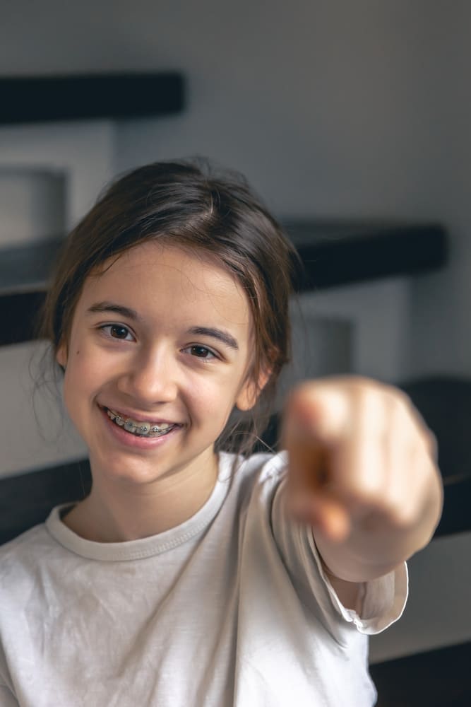 Ortodonzia Pediatrica - Foto di una bambina con l'apparecchio che sorride felice.